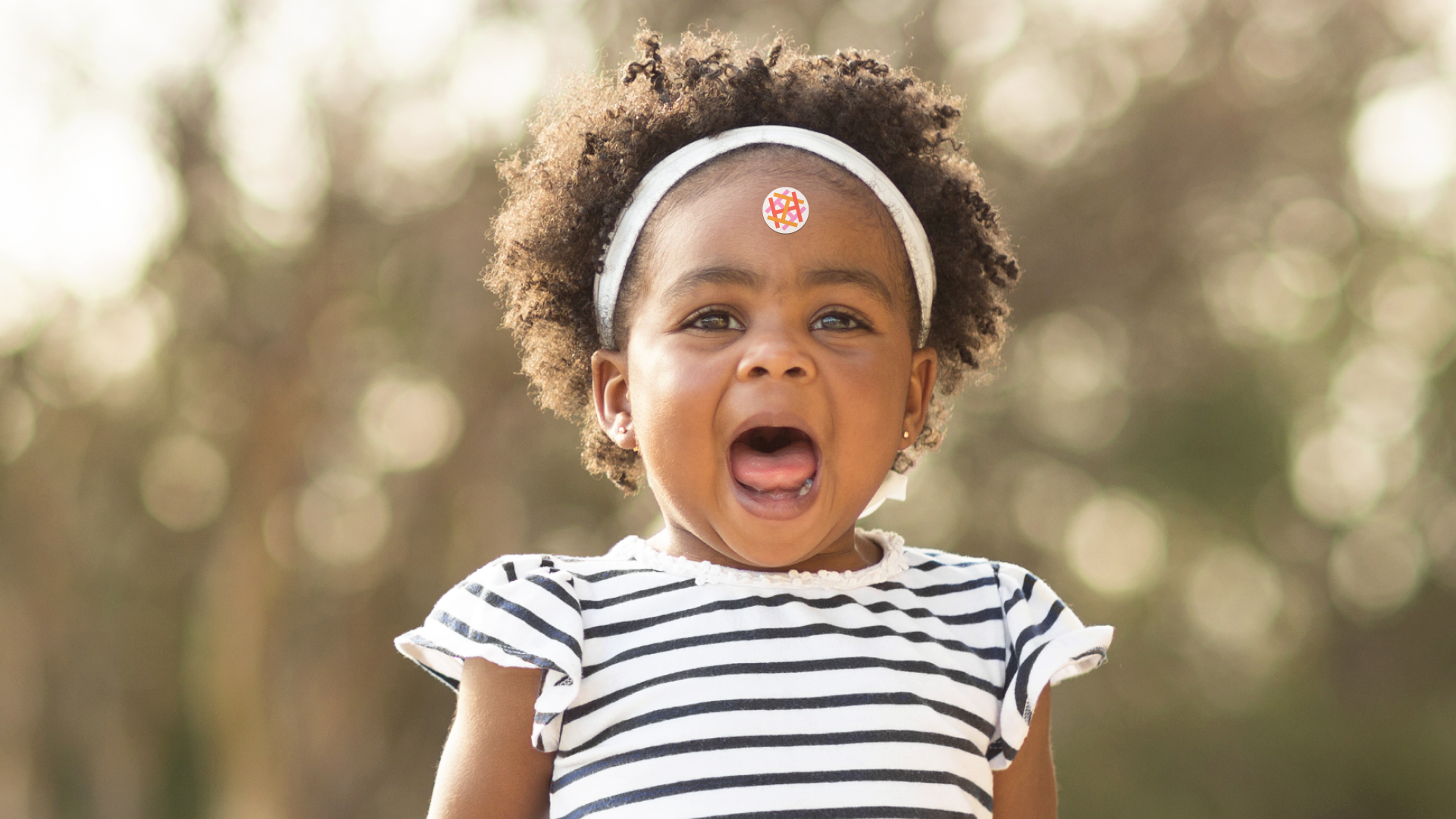 baby with a sticker on the forehead. Copyright Cotton Design, Talia Cotton