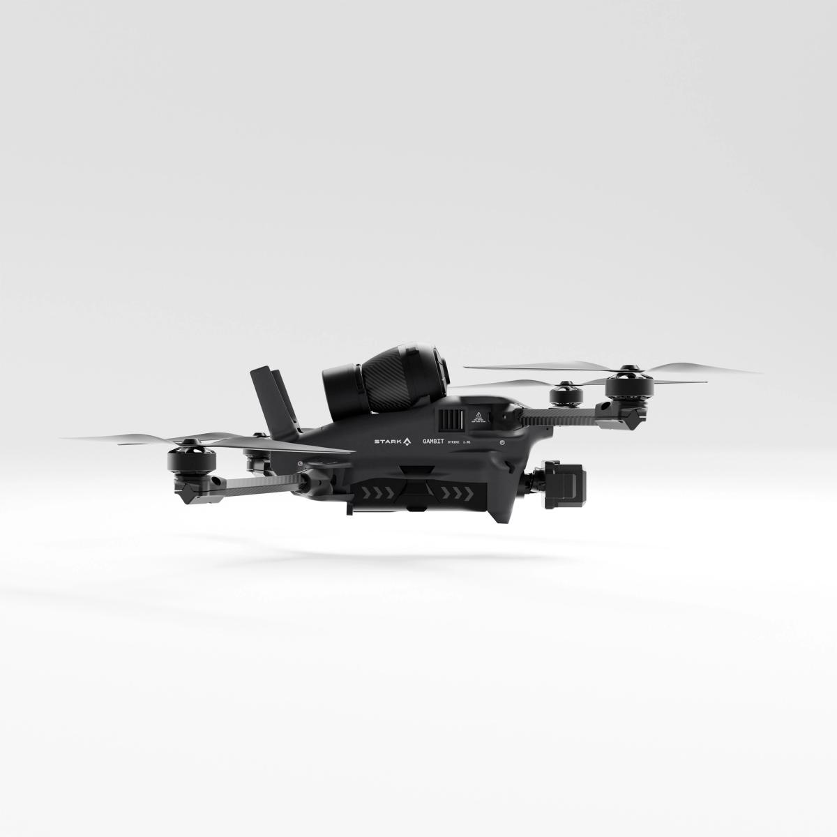 A black STARK GARNET drone with a gimbal camera underneath and a large spotlight or sensor mounted on top, hovering against a white background.