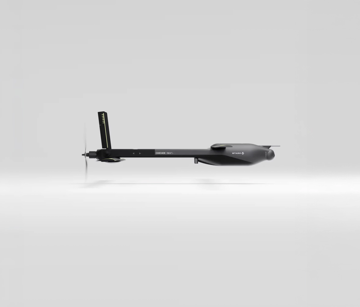 A sleek, dark grey drone with a front propeller and long body, viewed from the side against a light background.