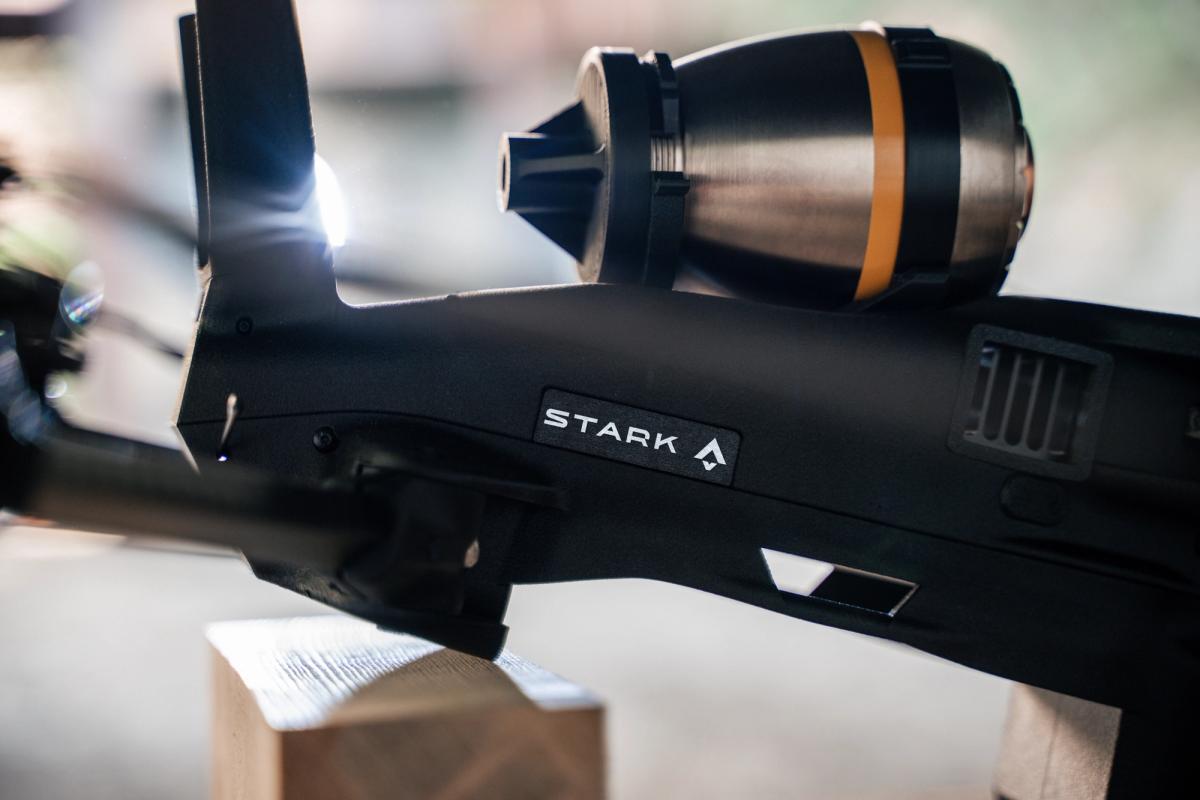 A dark device branded "STARK" with a bright light and a metallic cylindrical attachment featuring an orange stripe.
