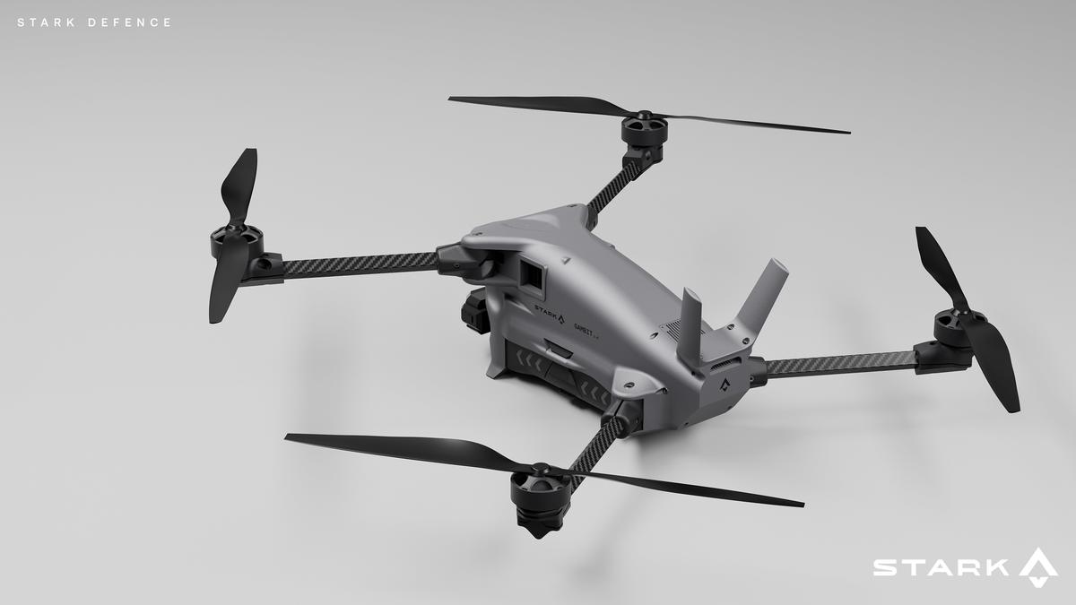 A grey quadcopter drone with black propellers and carbon fiber arms, branded Stark Defence.