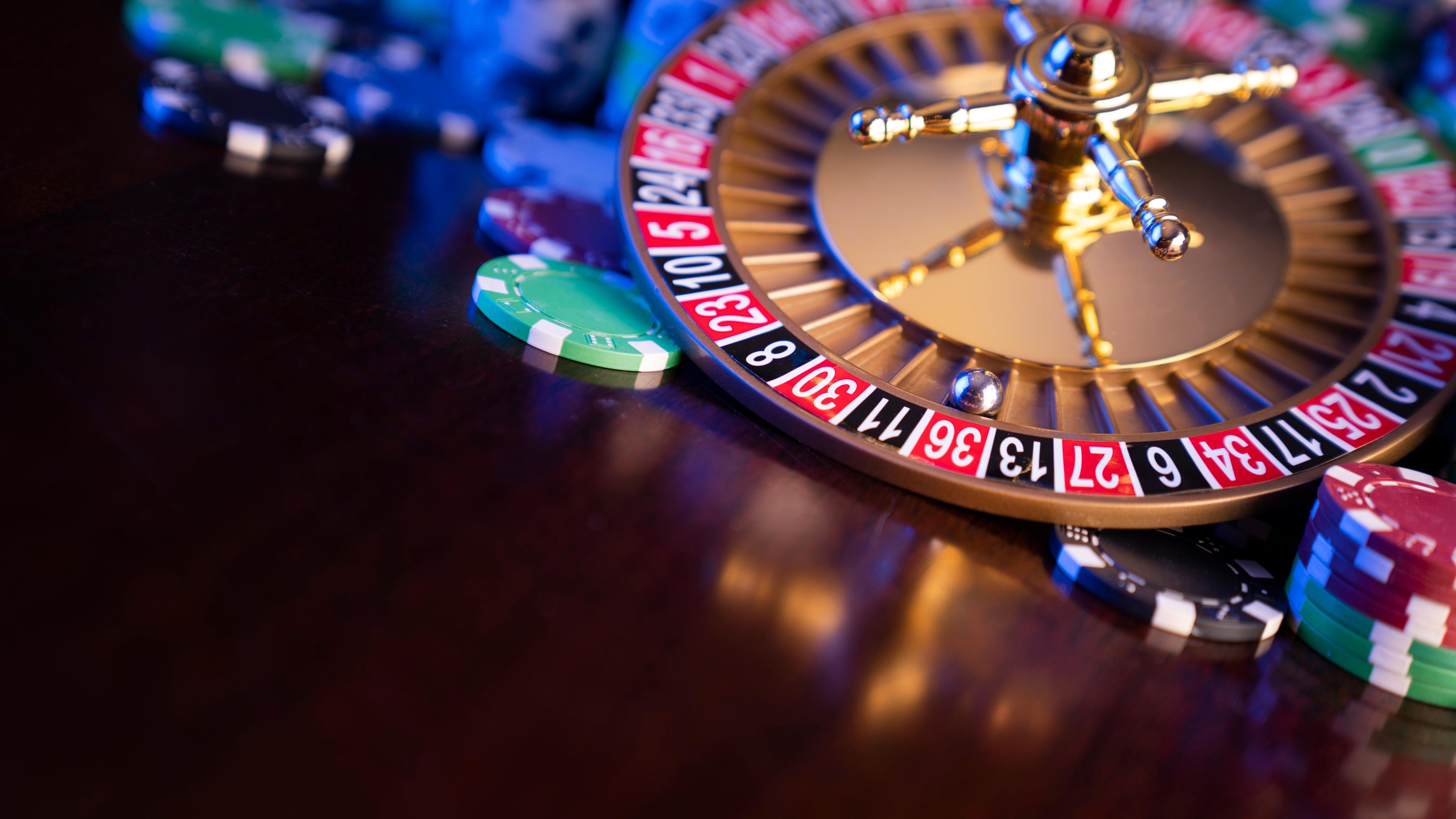 På billedet ses en roulette liggende på et brunt bord. Rundt om rouletten er der en masse forskellige jetoner. Roulettekuglen ligger på rødt tal nummer 36, men er ellers ikke i gang med et spil.