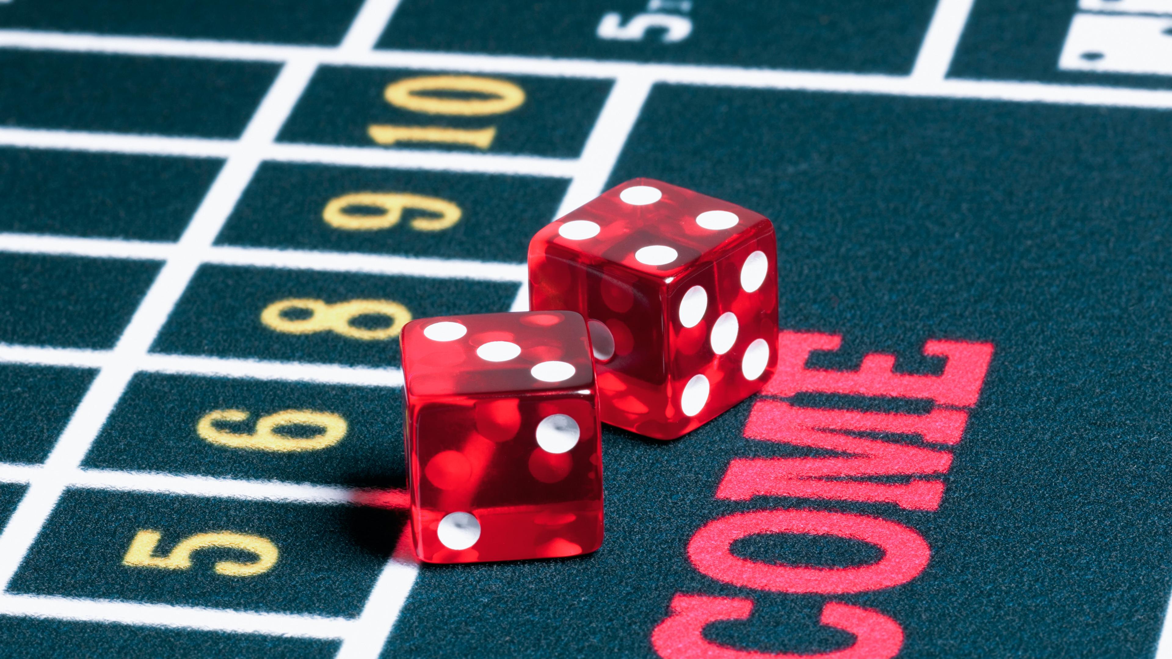 På billedet ses et udsnit af et kasinobord. På bordet er to røde terninger. Den ene terning har tallet 3 med forsiden opad, og den anden terning viser tallet 4.