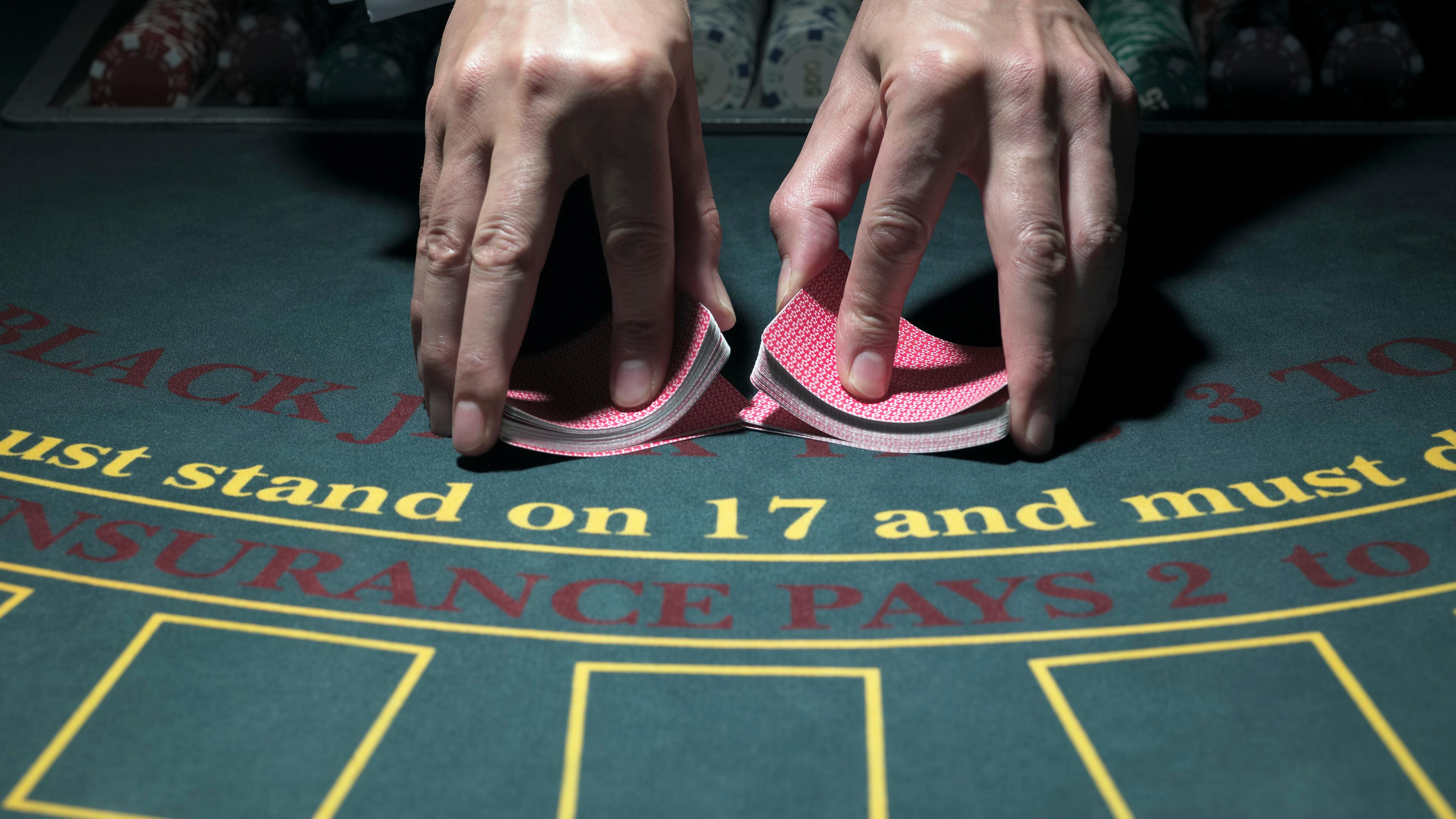 En person blander kort ved et blackjack bord.