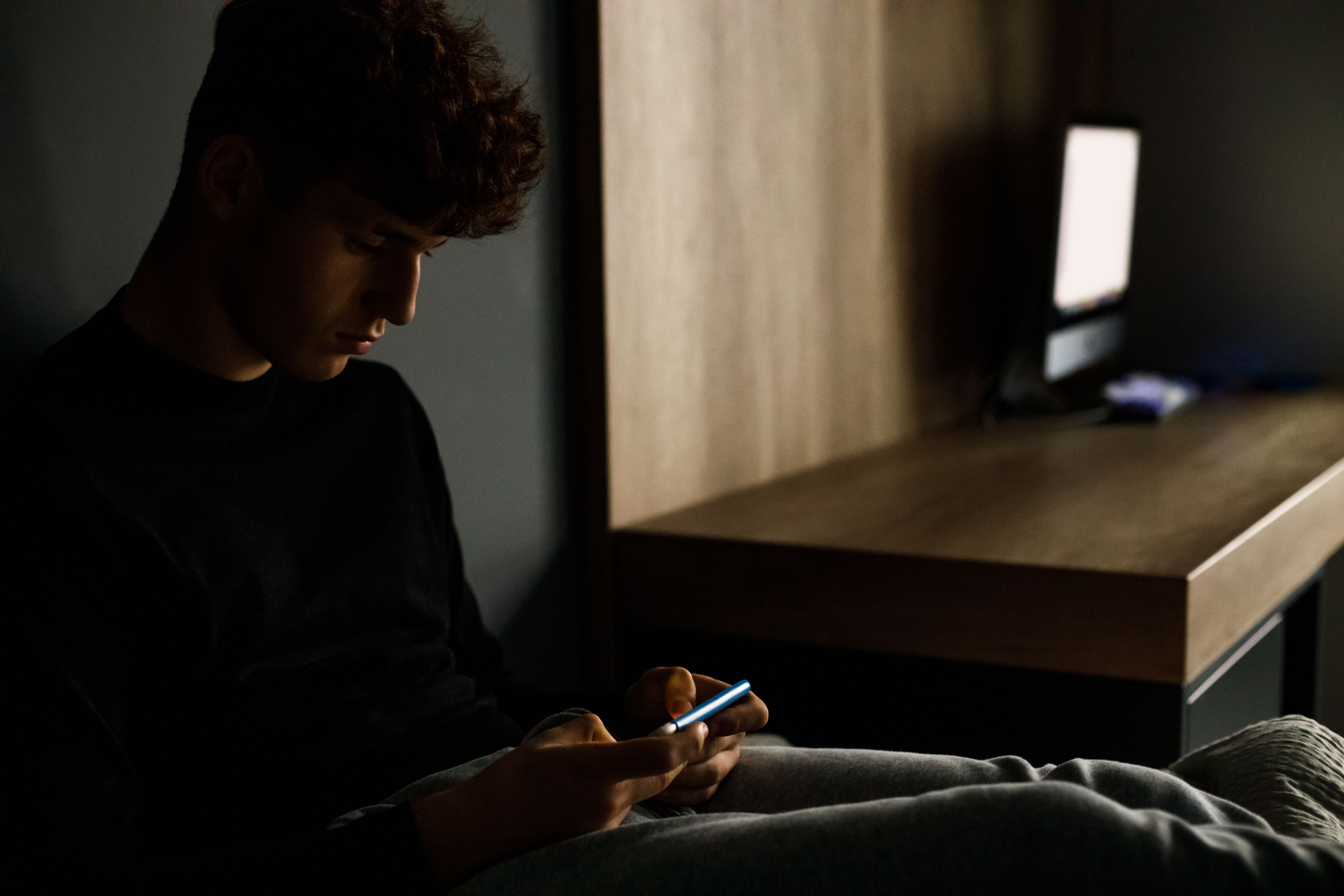 En dreng sidder med sin mobiltelefon.