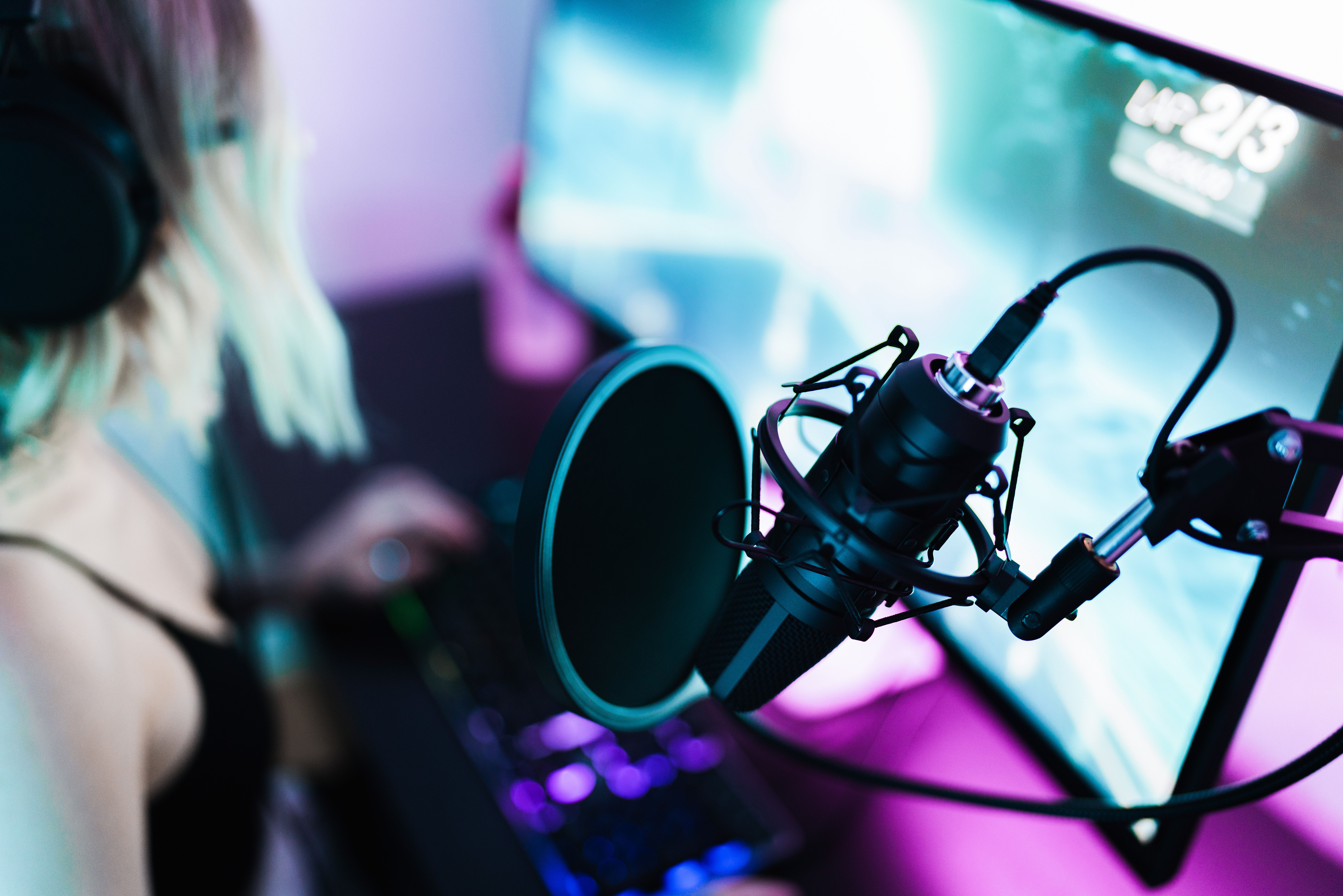 En pige sidder foran en computerskærm med en mikrofon i forgrunden 