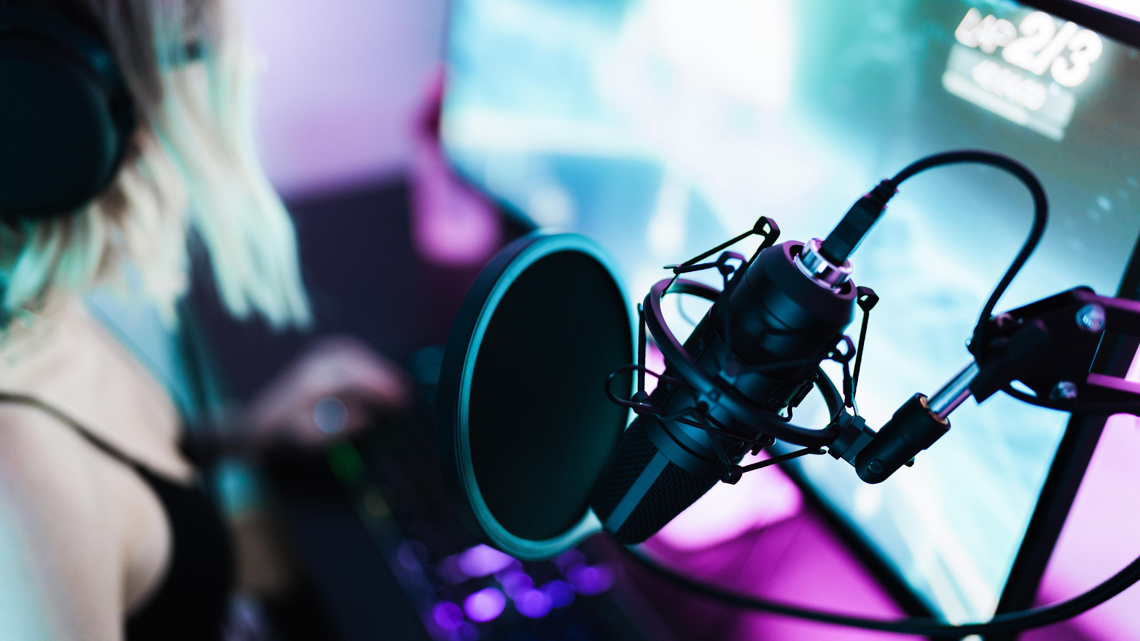 En pige sidder foran en computerskærm med en mikrofon i forgrunden