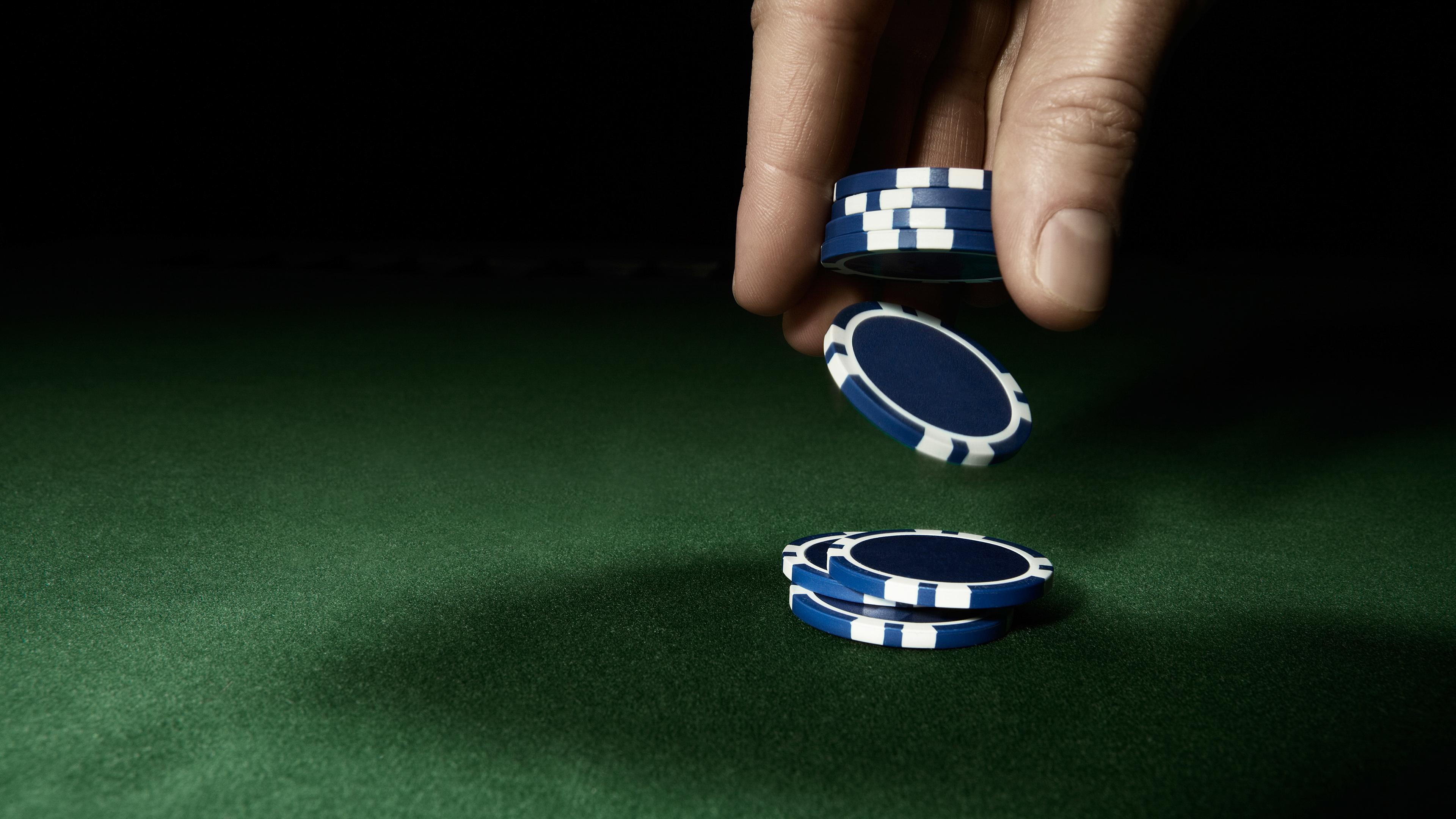 Grønt pokerbord. En hånd slipper blå jetoner.