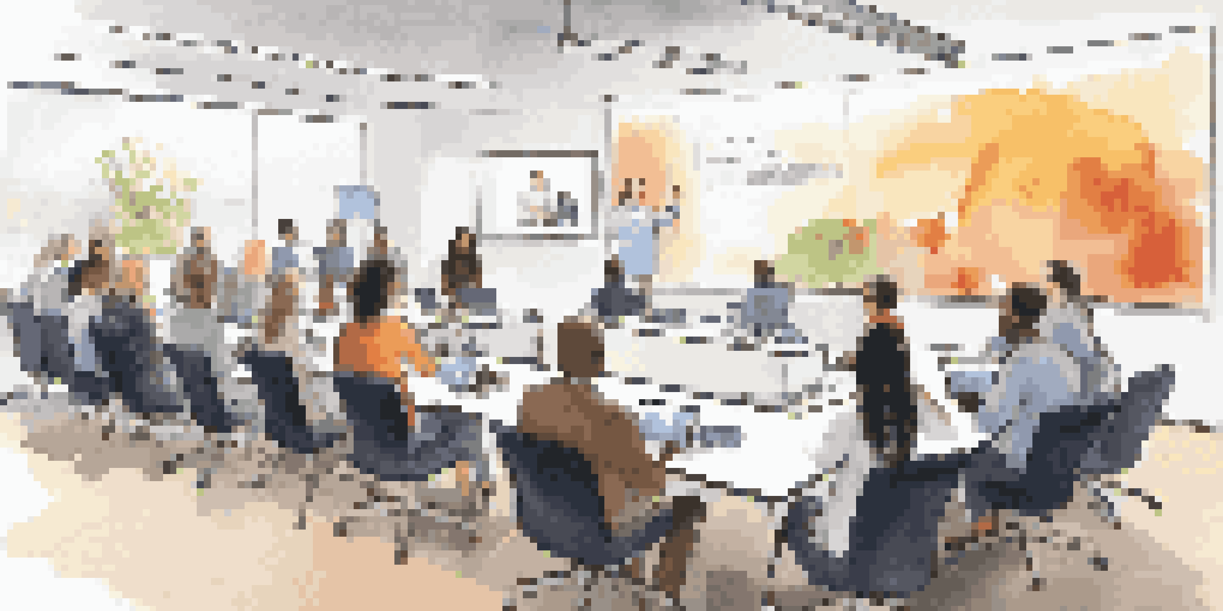 A diverse group of individuals participating in a webinar, with a large presentation screen and modern technology.