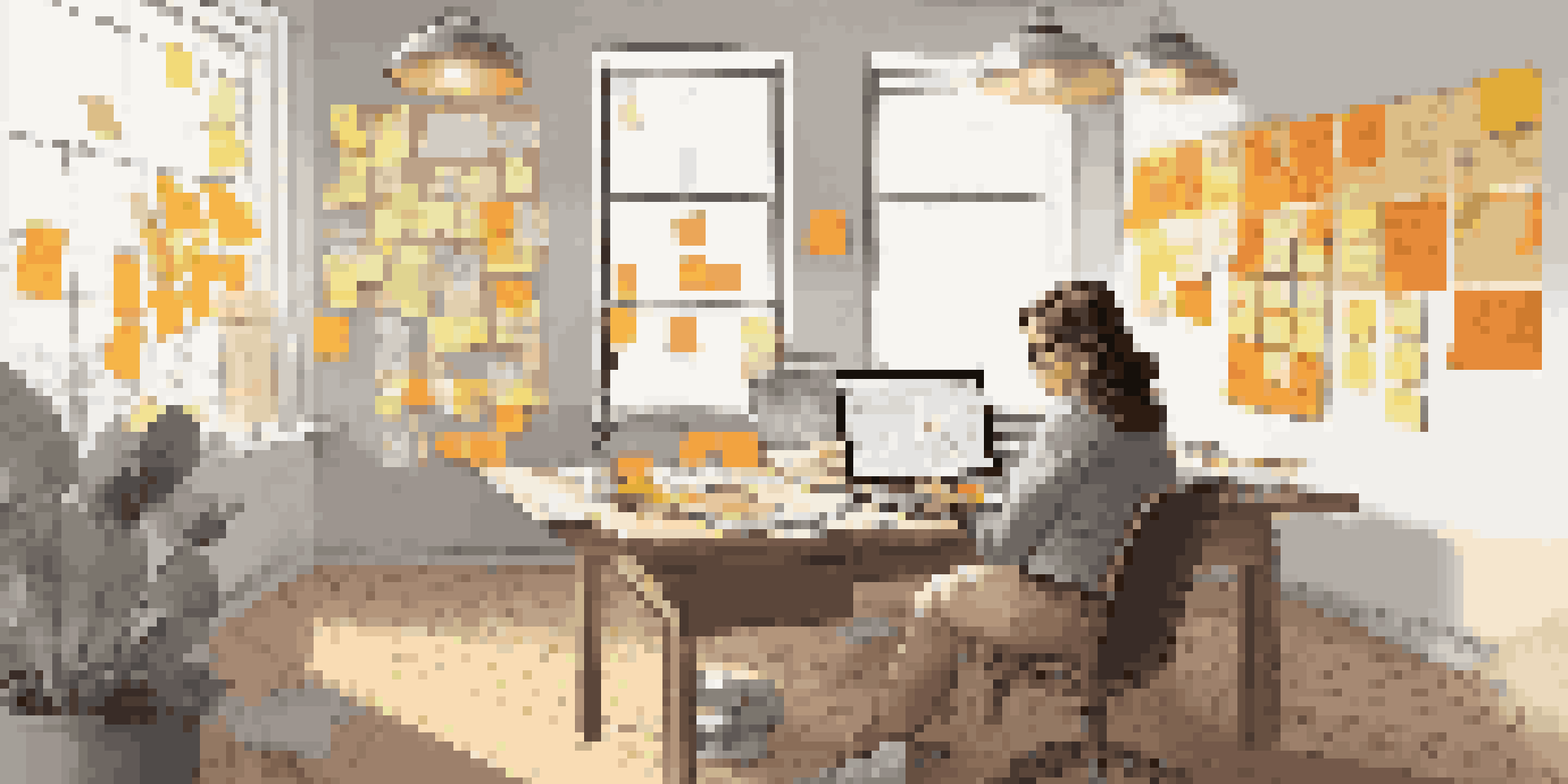 A woman designer working at a desk with colorful sticky notes and user journey maps on the wall, illuminated by natural light.