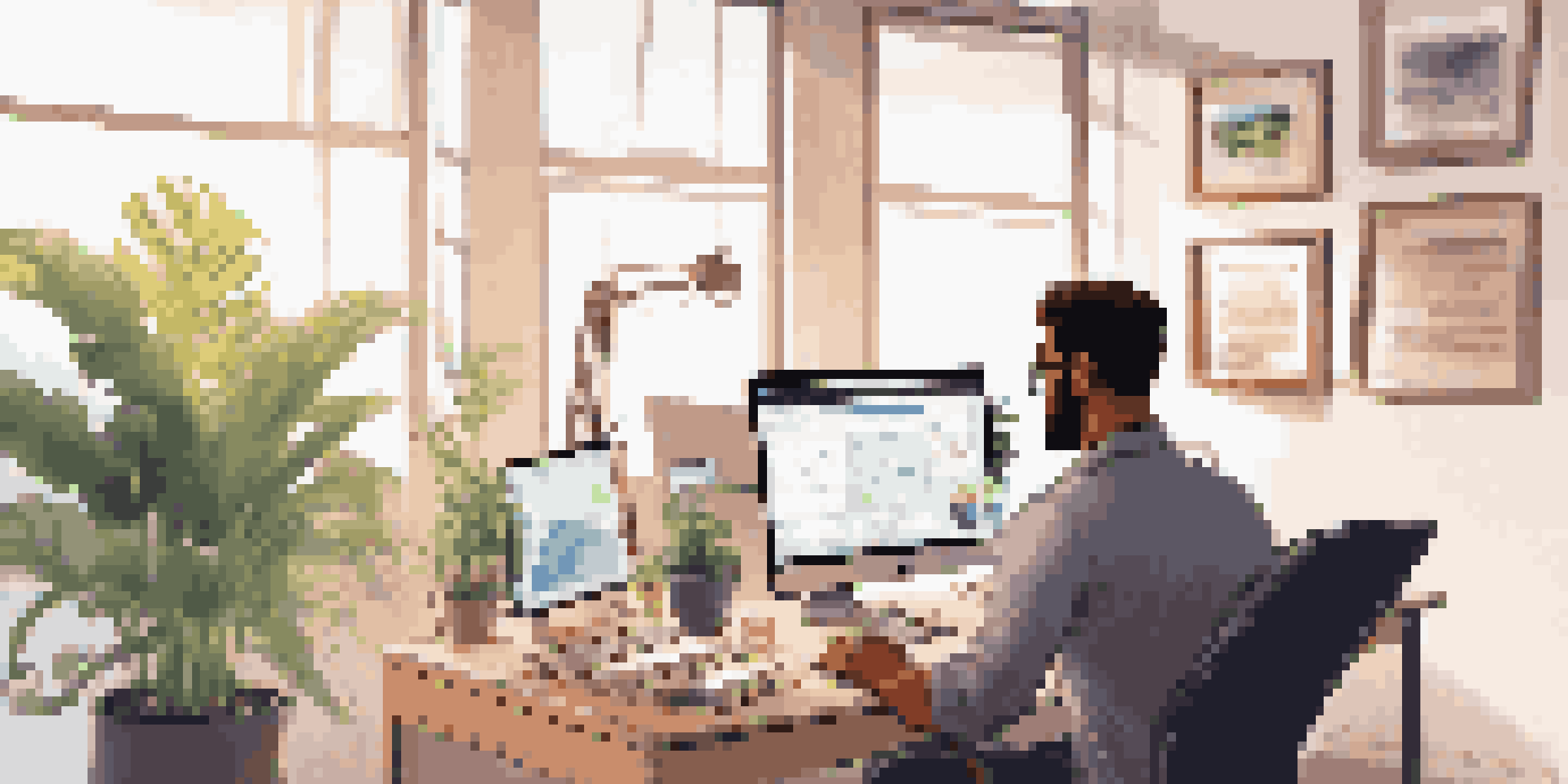 A project manager working at a desk with multiple screens displaying project management tools in a bright room.
