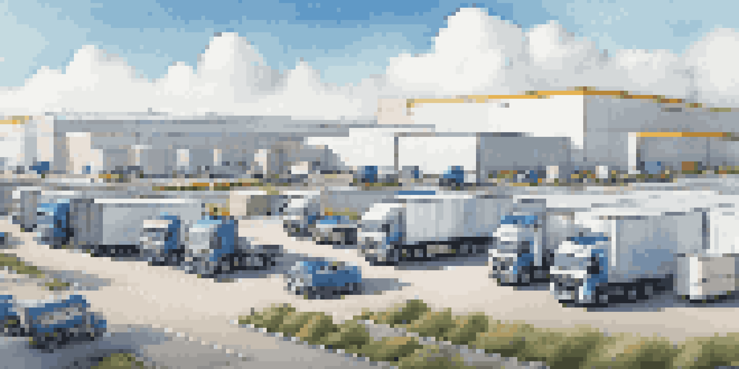 A busy logistics center with trucks, digital screens, and workers using tablets in a sunny environment.