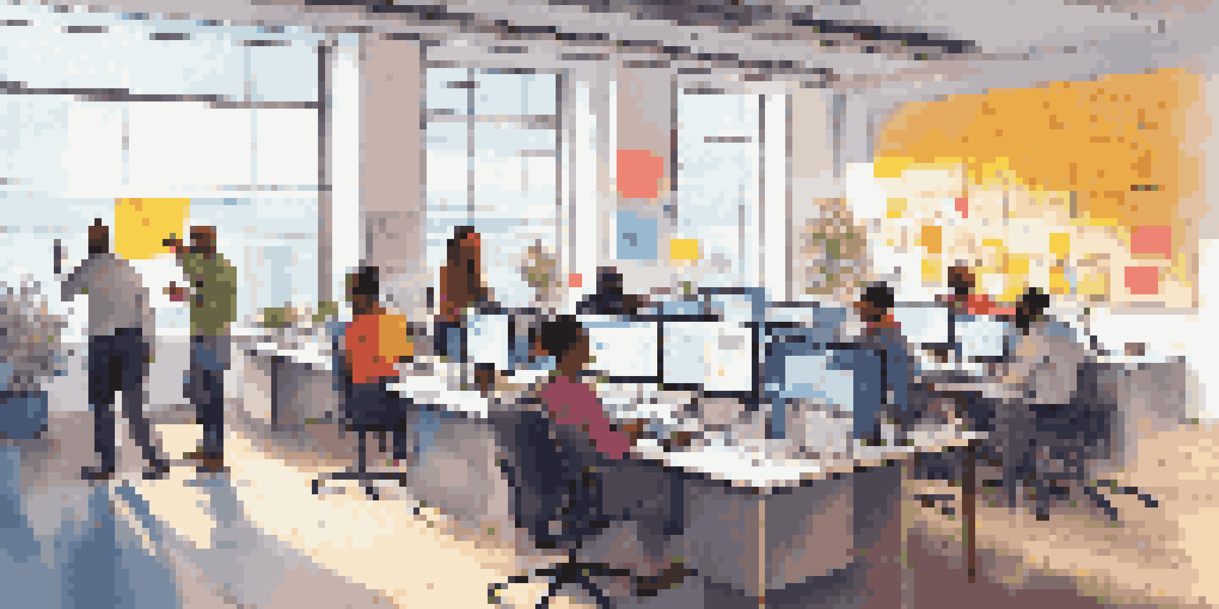 A diverse team working together in a modern office environment, focusing on low-code development with laptops and visual programming interfaces.