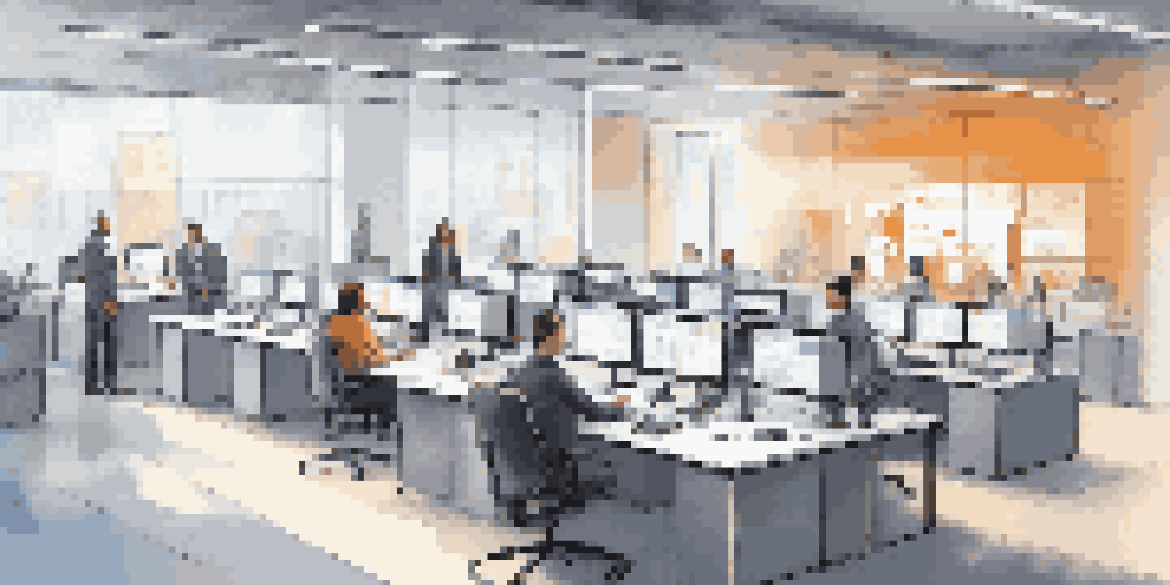 A modern office with employees using computers alongside robotic arms assisting in their tasks, illuminated by warm ambient lighting.