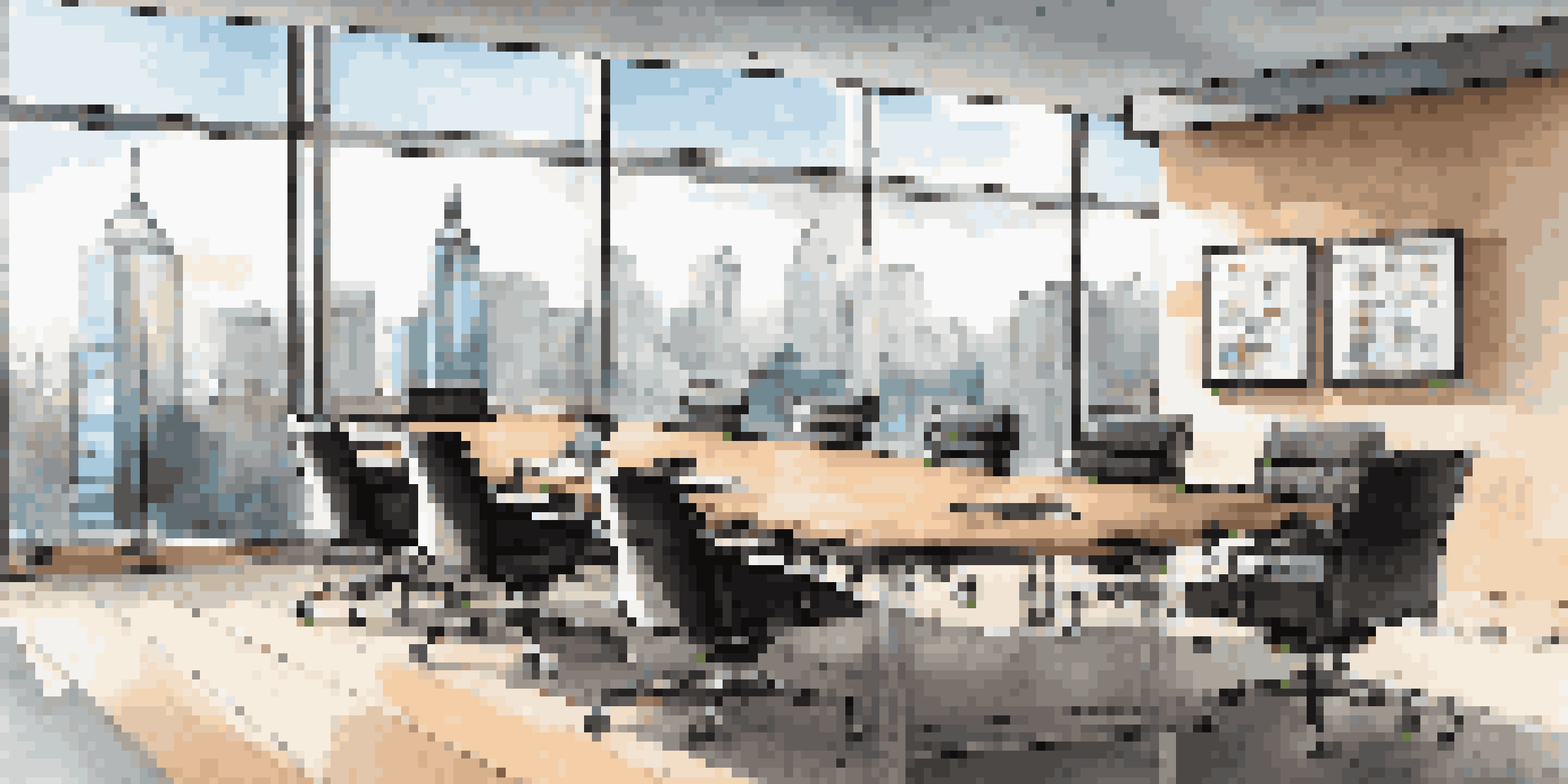 A modern office conference room with a wooden table and black chairs, filled with natural light and a view of the city skyline.