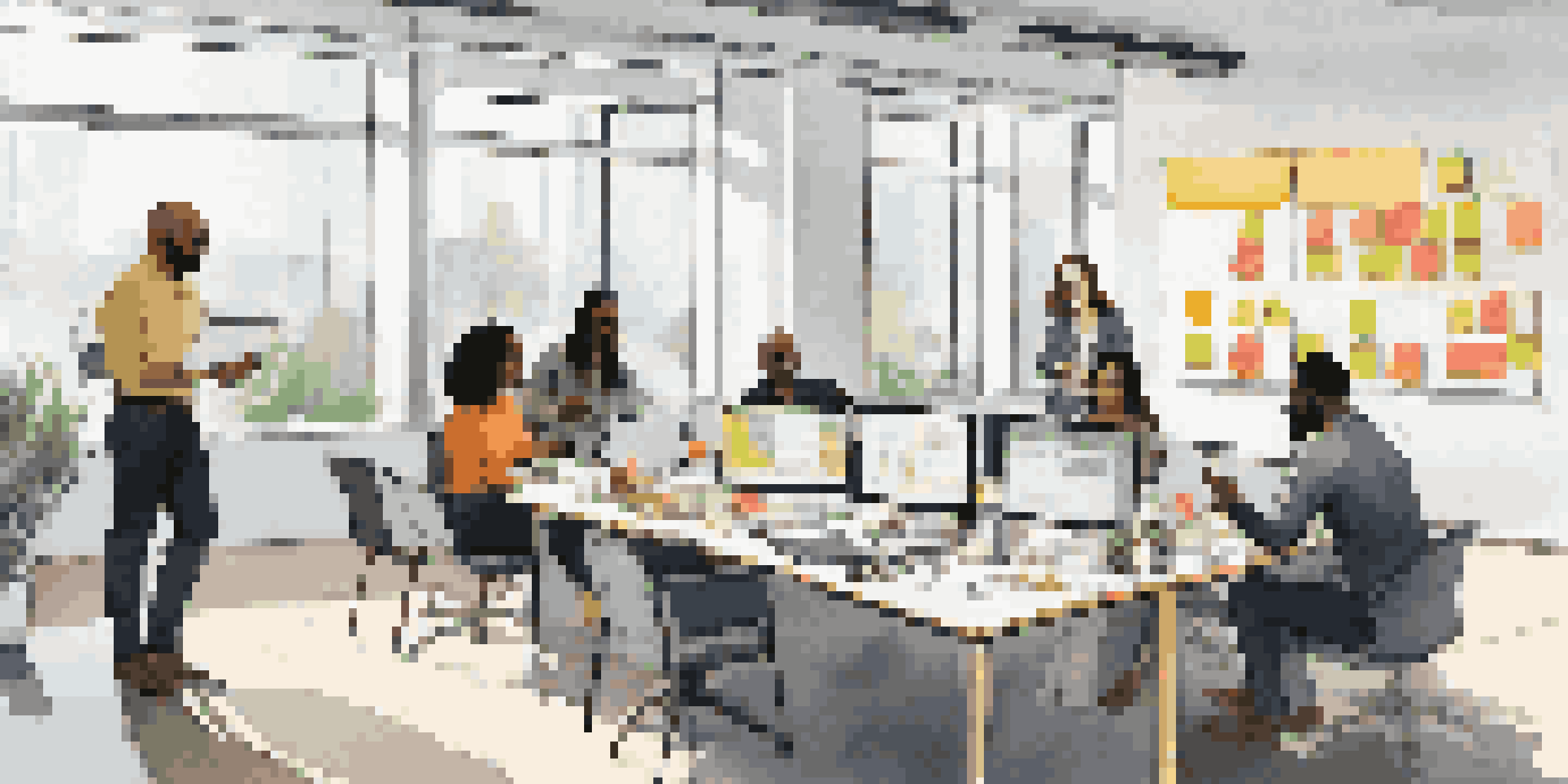 A diverse team of professionals collaborating in a bright office, surrounded by laptops and sticky notes.