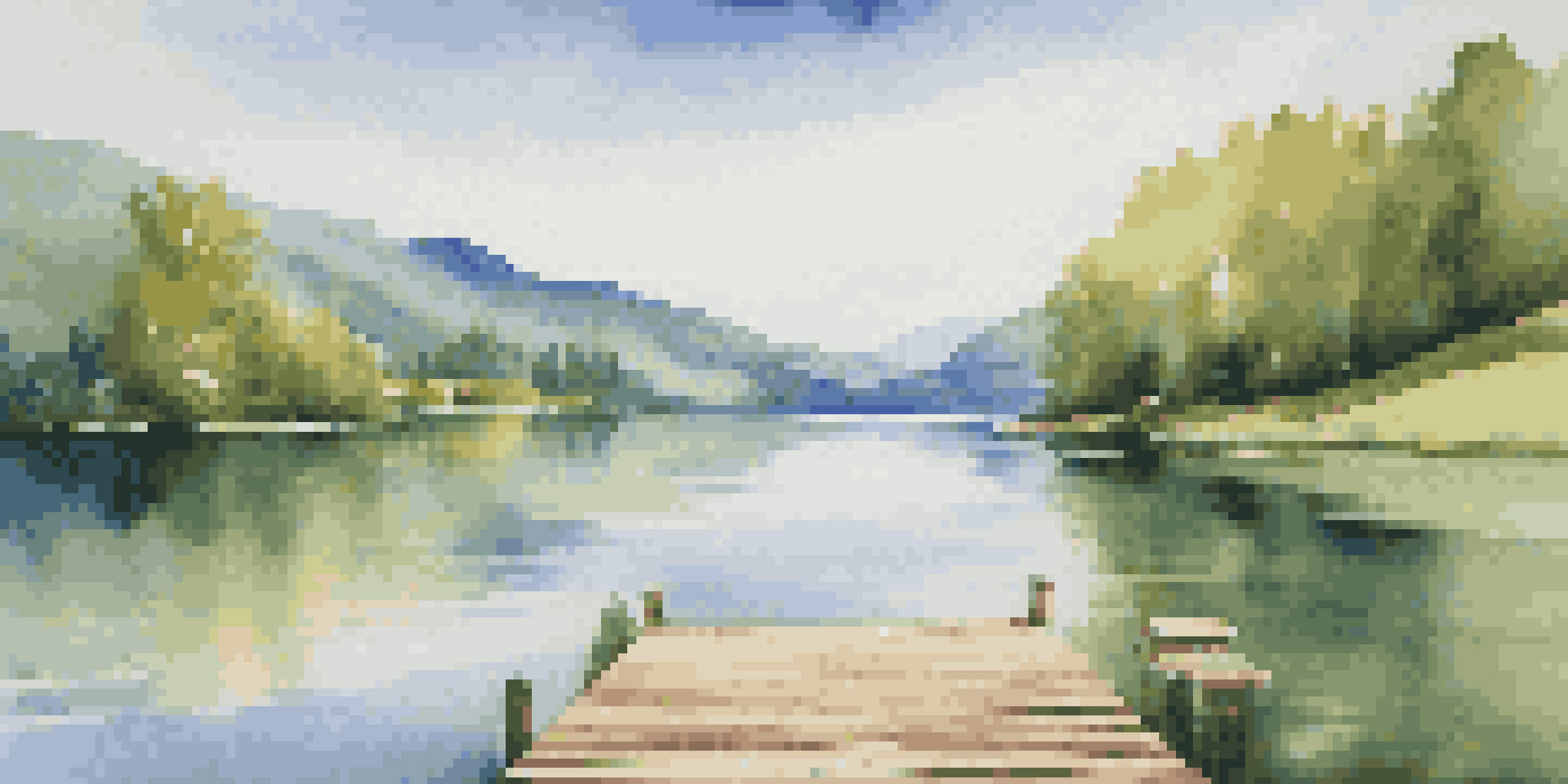 A peaceful lake surrounded by green mountains with a clear blue sky, featuring a wooden dock extending into the water.