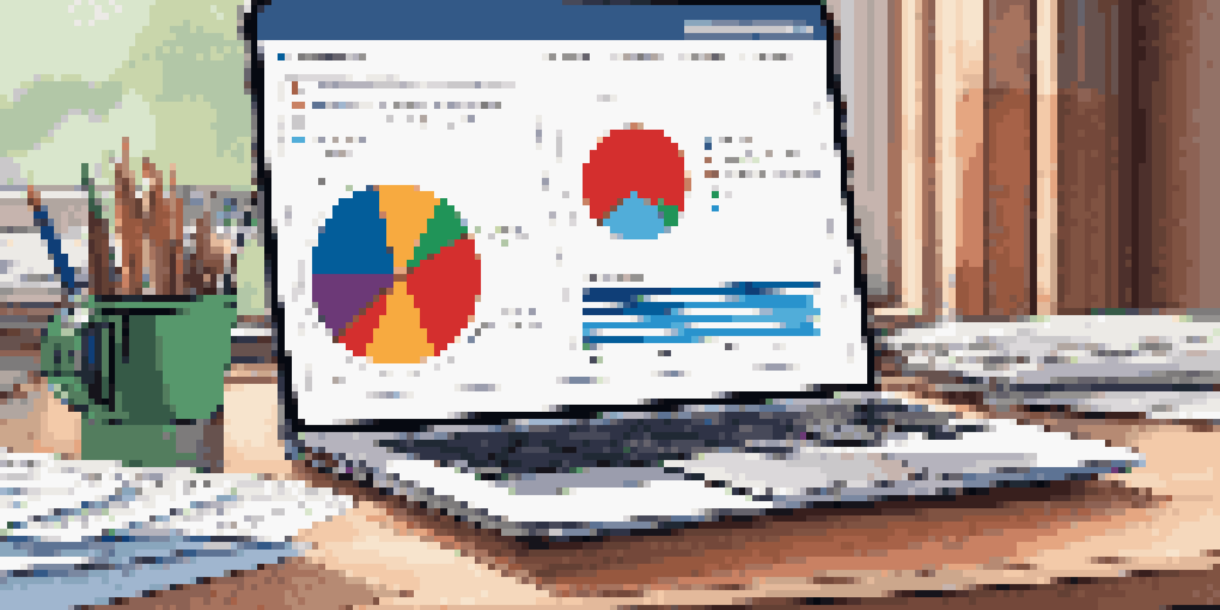 A close-up view of a colorful pie chart on a desk, with a laptop and financial documents in the background, showcasing vibrant segments in red, green, and blue.