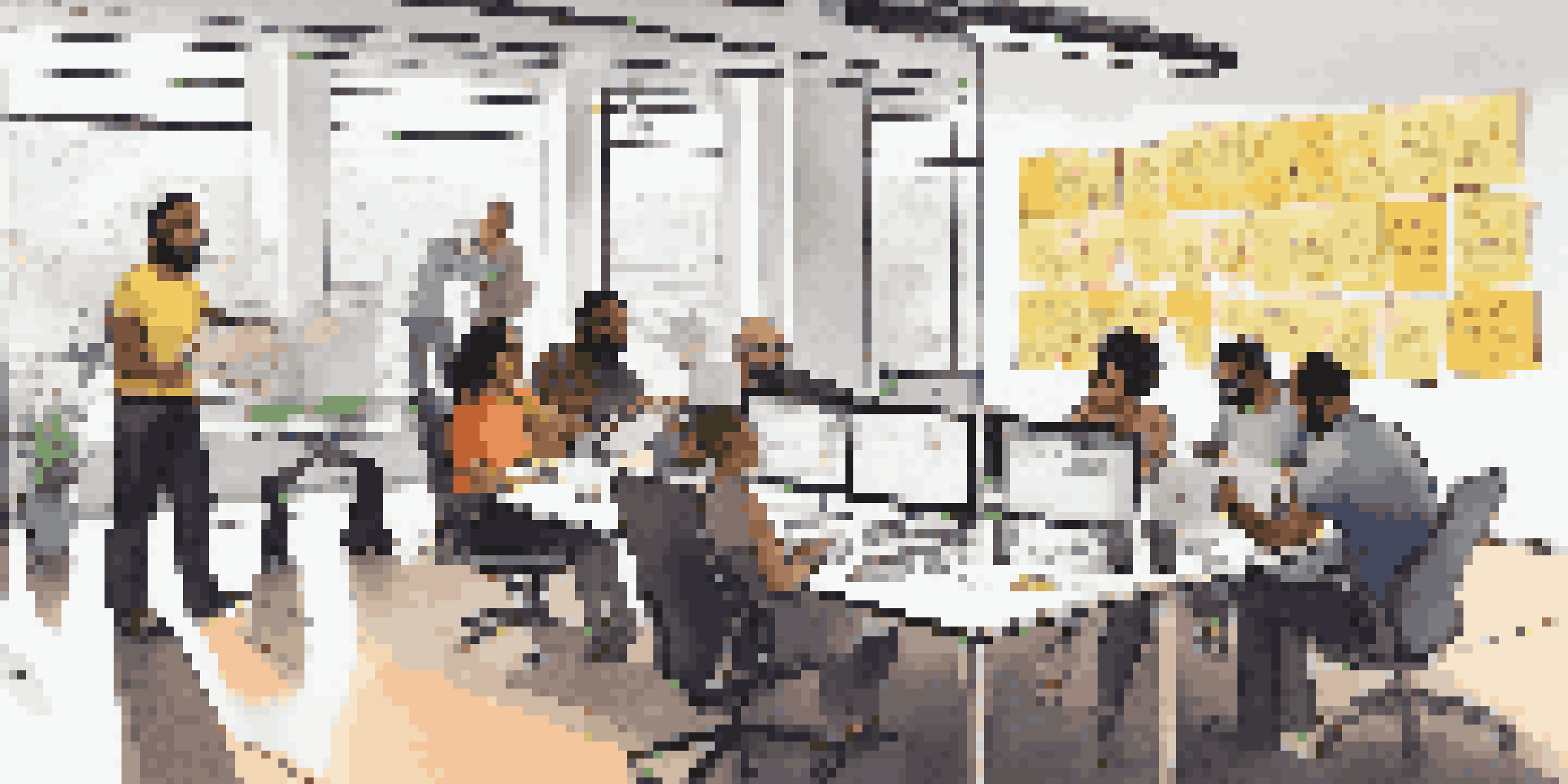 A group of diverse software developers collaborating at a conference table with laptops and sticky notes, surrounded by posters of agile methodologies.