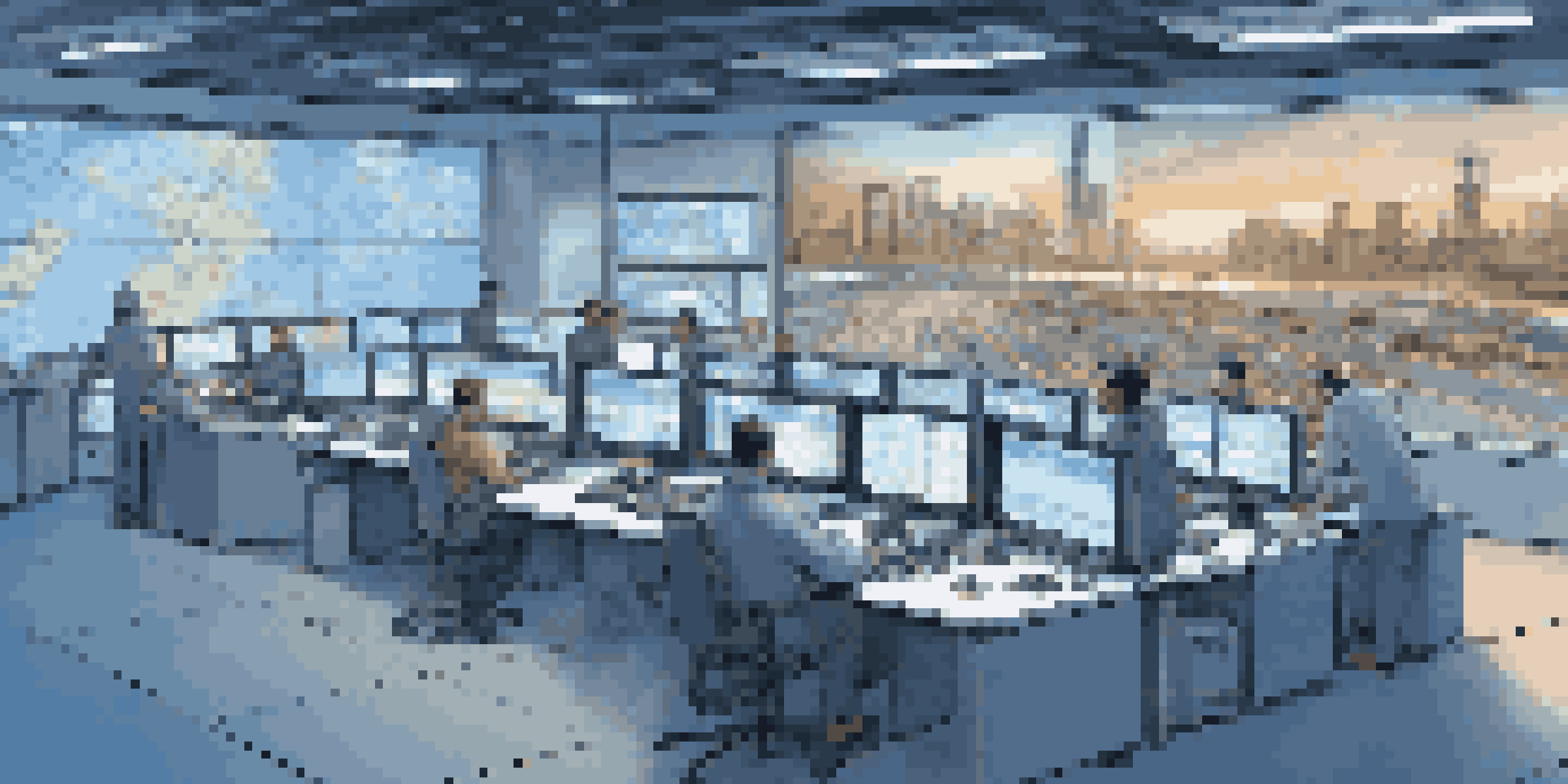 A control room for fleet management with operators analyzing real-time vehicle tracking data on multiple screens, illuminated with blue lights.