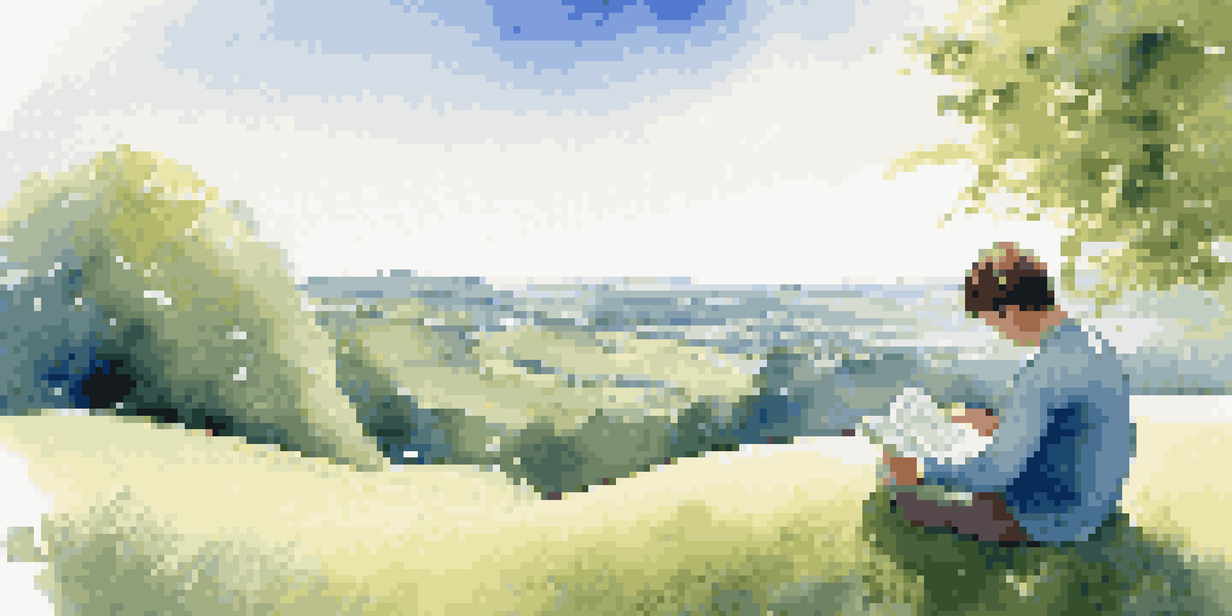 A person reading a book on a grassy hill under a blue sky with clouds, symbolizing digital detox.