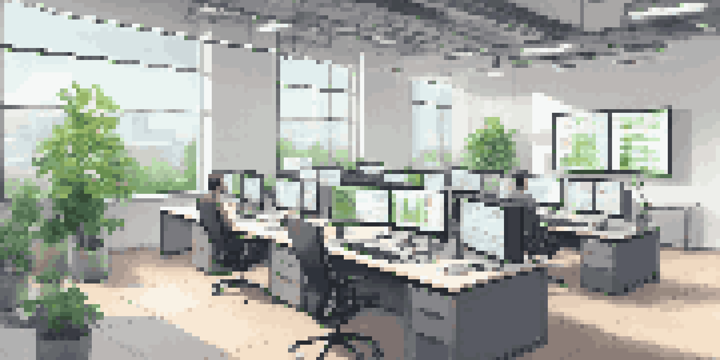 A bright modern office with computer screens showcasing UI testing metrics and graphs, surrounded by plants and a minimalist design.