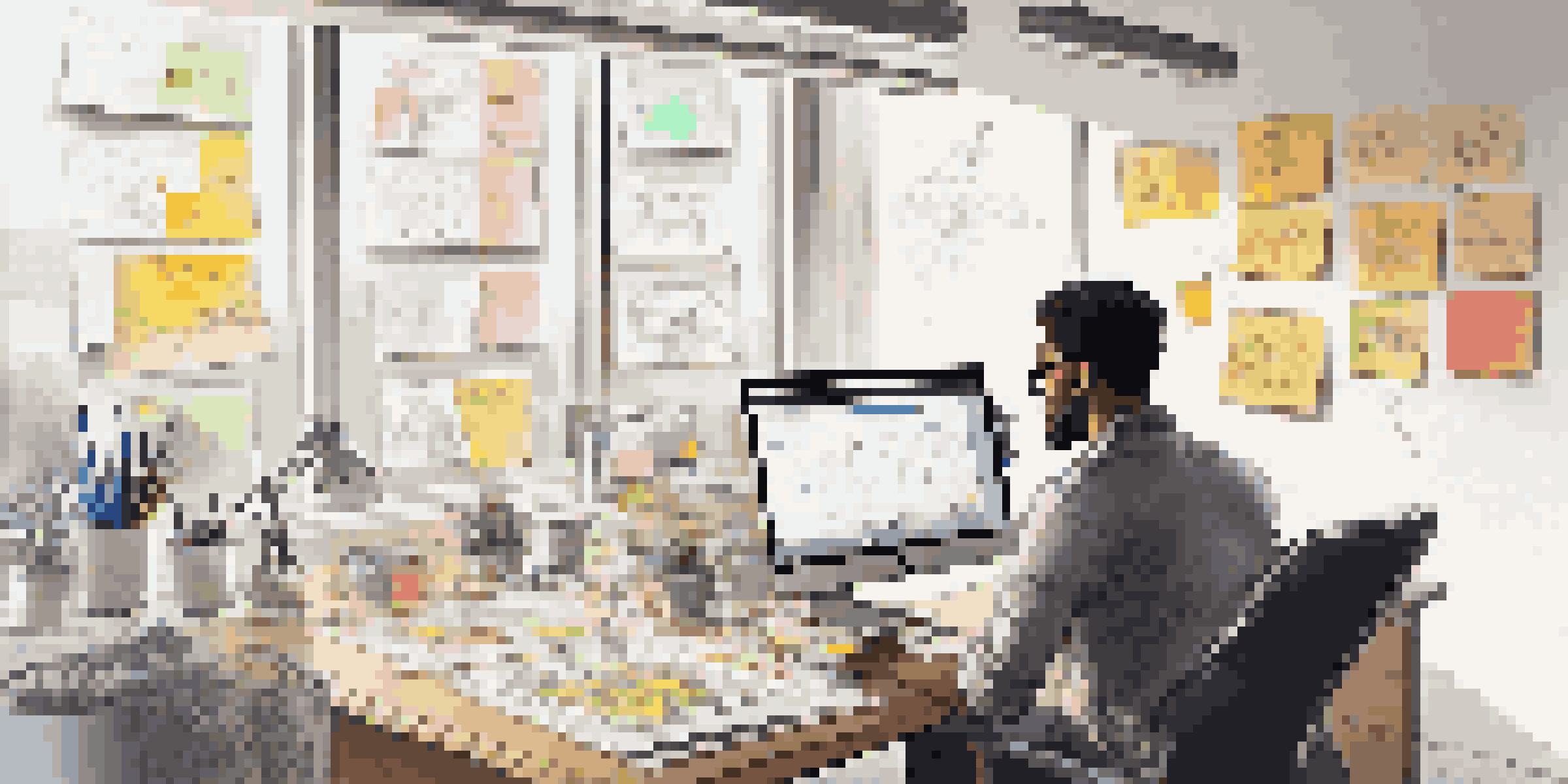 A designer working in a bright and colorful workspace filled with sketches, digital tools, and user feedback data on a screen.