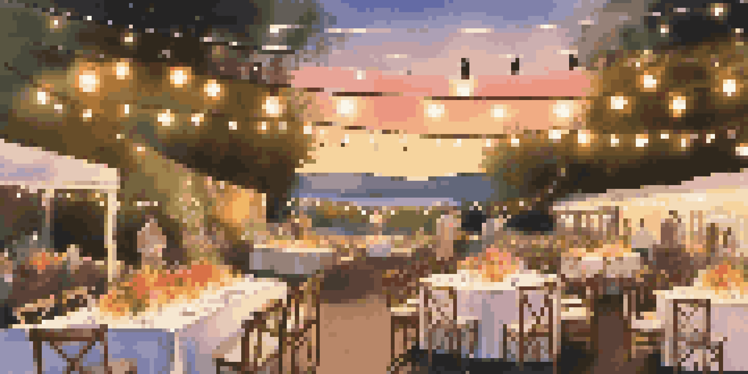 An outdoor event space decorated with colorful decorations and string lights, illuminated by a warm sunset.