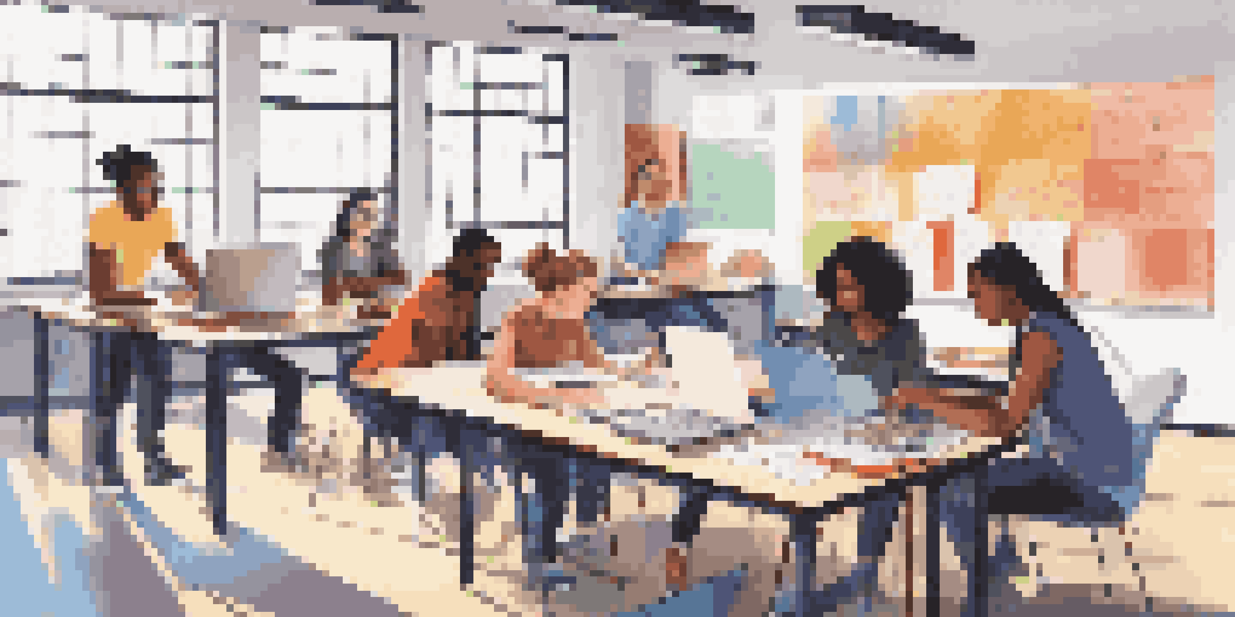 A diverse group of students working together in a modern classroom, using laptops and discussing projects.