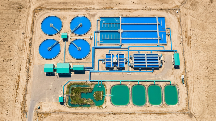 Aerial view of a treatment facility surrounded by dry cracked landscape with tertiary treatment tanks and reuse pipelines