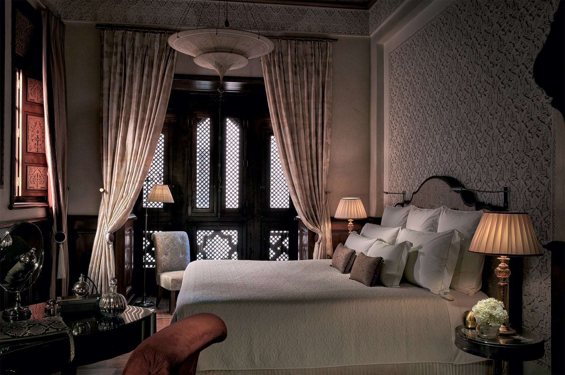 An ornate riad bedroom with carved plaster and mashrabiya screens
