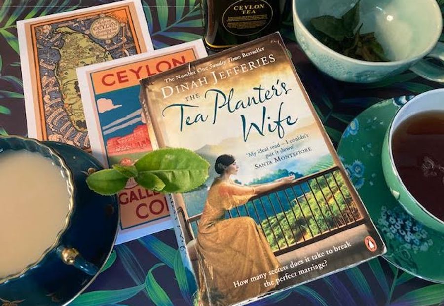 A photo of a number of books resting on a table next to a cup of tea