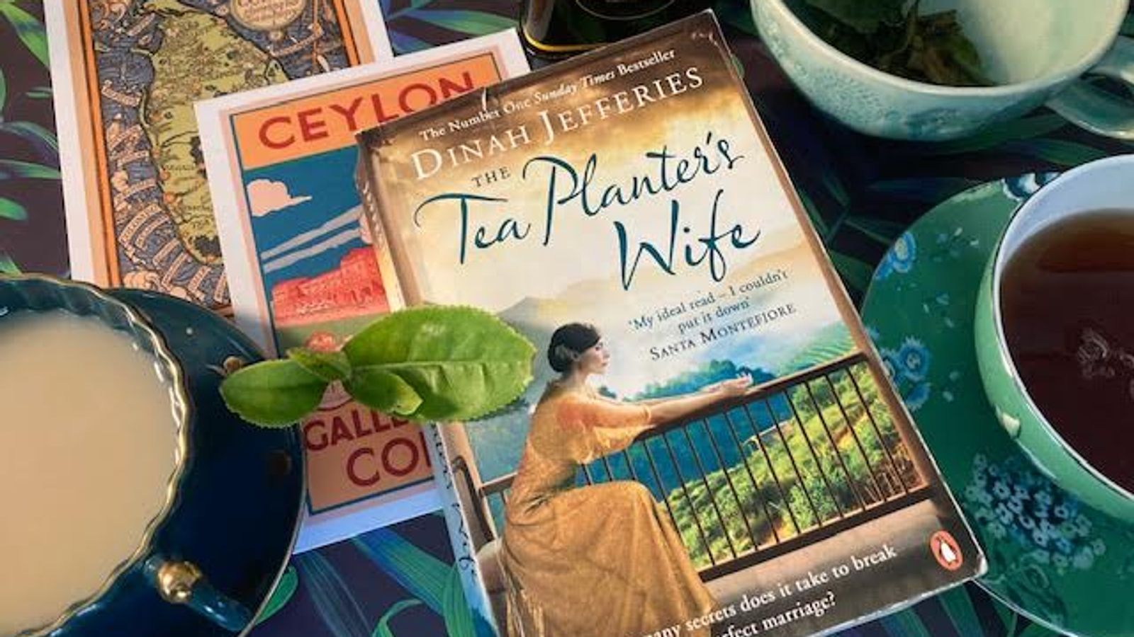 A photo of a number of books resting on a table next to a cup of tea