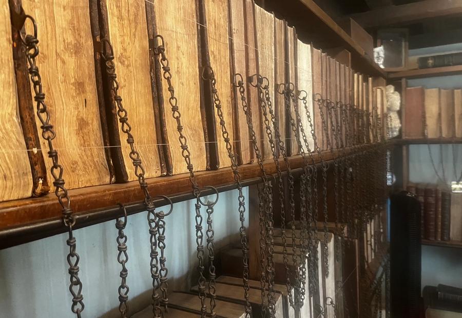 A picture from the Wimborne Minster chained library: rows of leather bound books attached to the shelves with chains. 