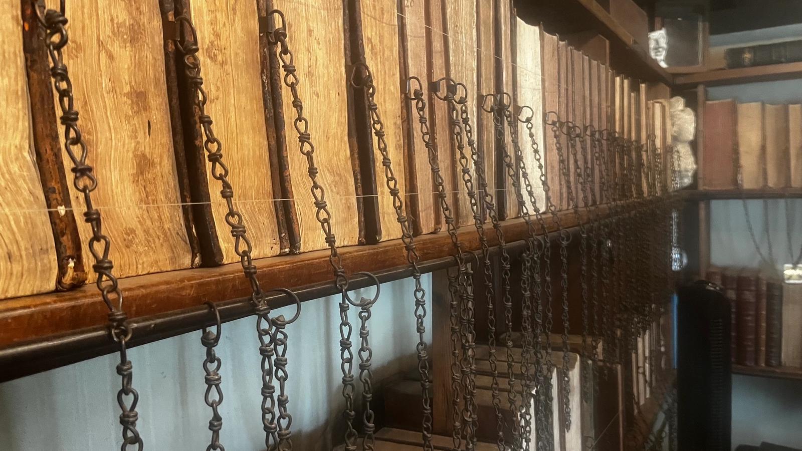 A picture from the Wimborne Minster chained library: rows of leather bound books attached to the shelves with chains. 