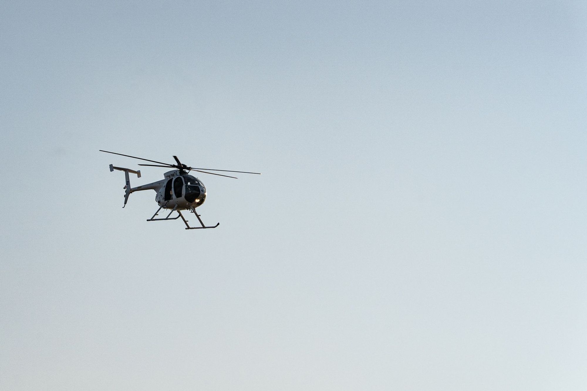 Light helicopter flying against a blue sky