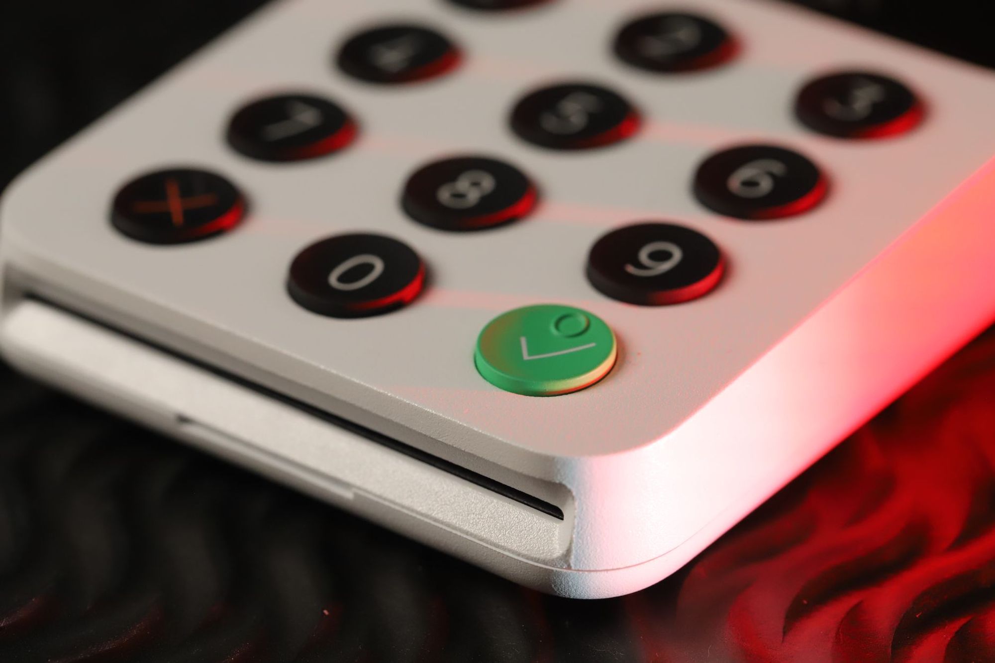 Close-up of a white card payment terminal keypad with a green confirm button
