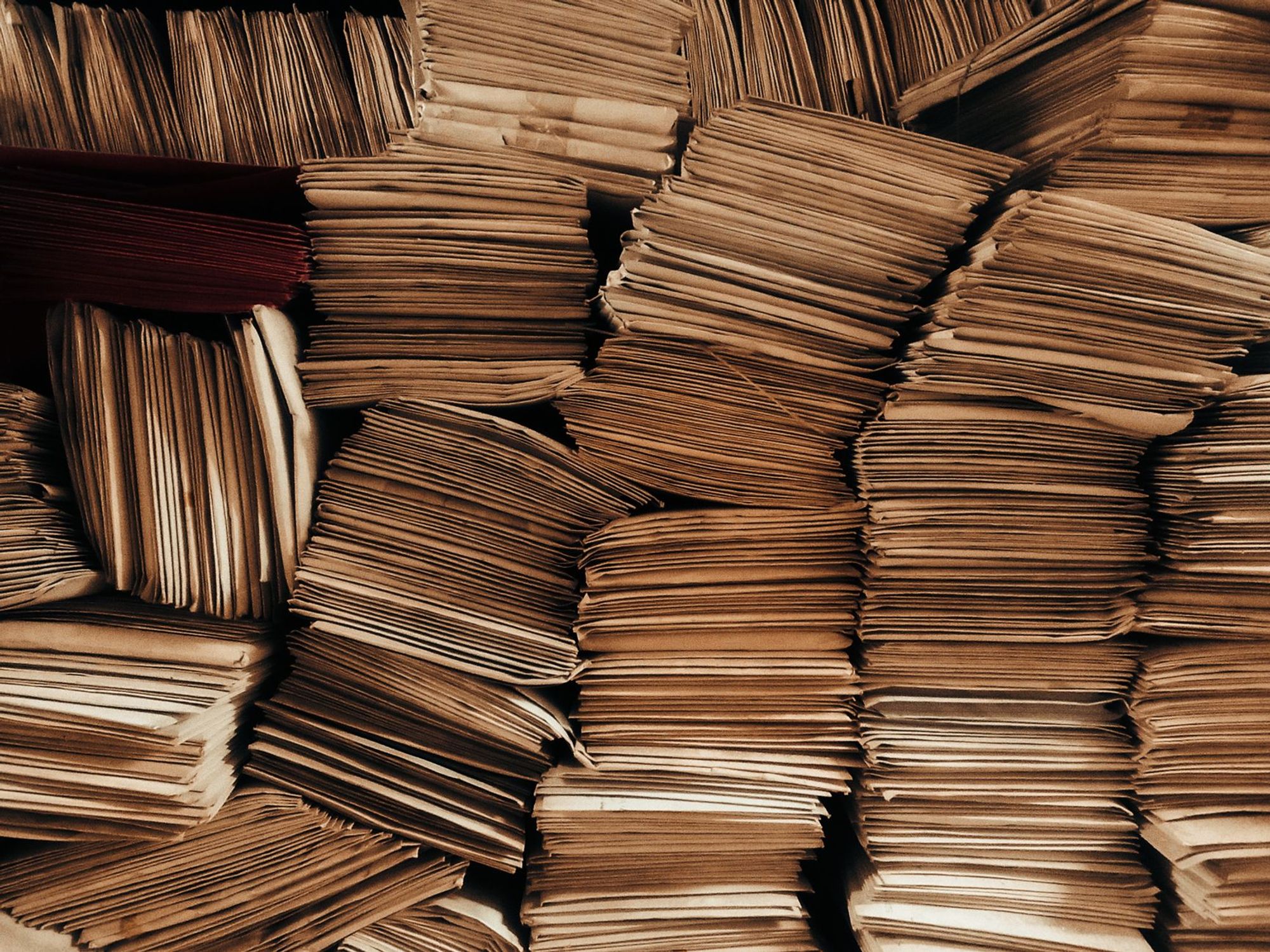 Stacks of old brown paper envelopes piled in uneven rows