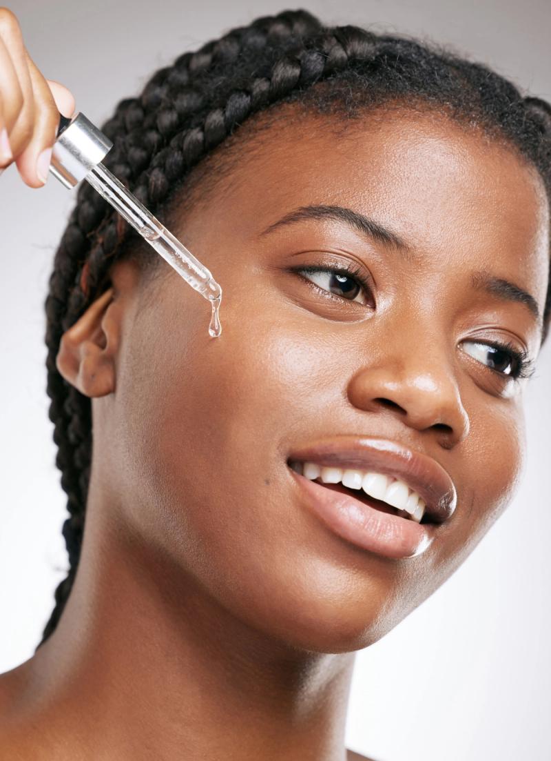 black woman applying serum to her face with a picker
