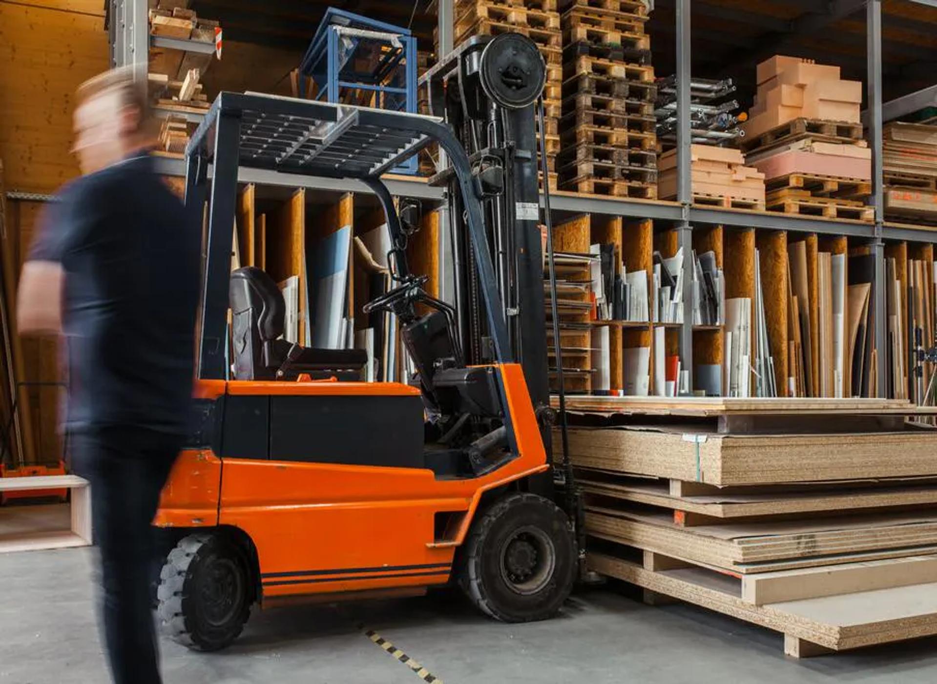A forklift carrying stacks of wood in a warehouse