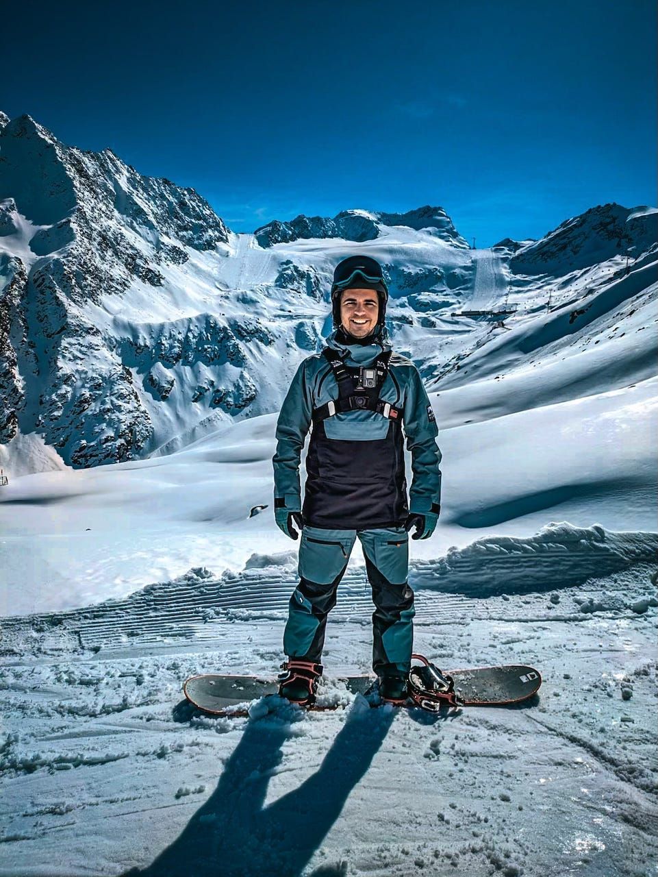 A person standing on snowboard in front of snowy mountains
AI-generated content may be incorrect.