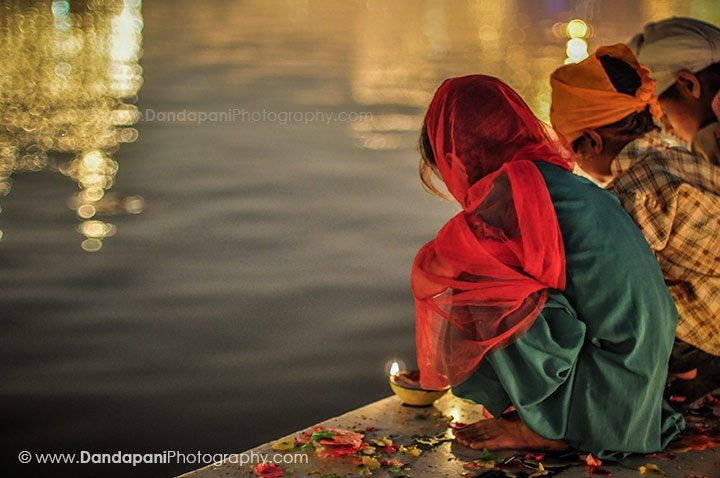 Children and adults light thousands of candles along the sacred pond.