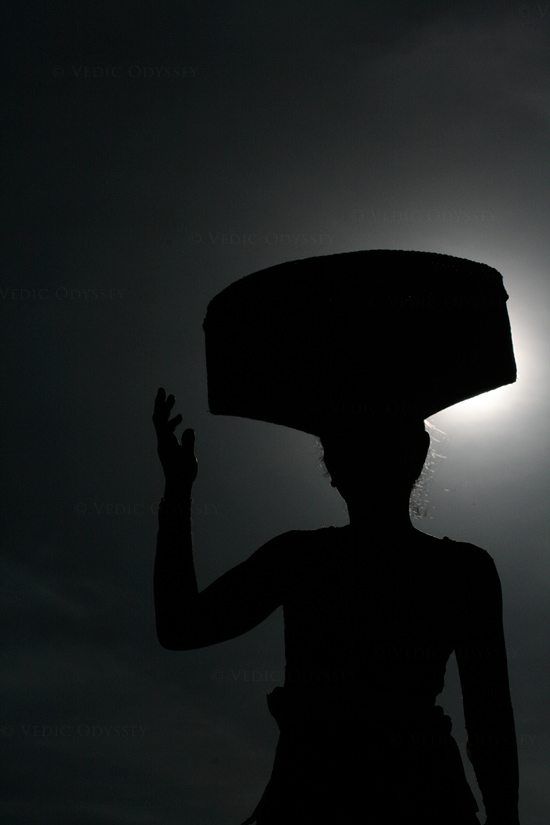 A Balinese lady goes about her day, carrying a basket on her head with groceries purchased at a local market. Ubud, Bali.