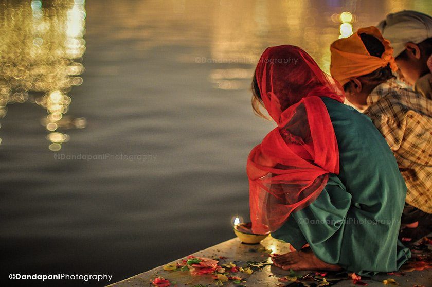 Children light lamps at the water's edge.