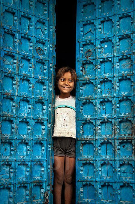 Indian girl standing next to colorful door