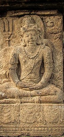 A carving on a large panel on one of the walls of the ancient Prambanan Hindu Temple in Central Java, Indonesia, depicts two students with they meditating guru.