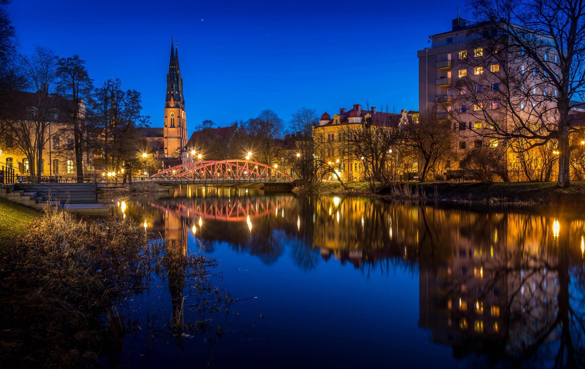 Evening lights of a bridge, the cathedral and parts of Uppsala from across the water