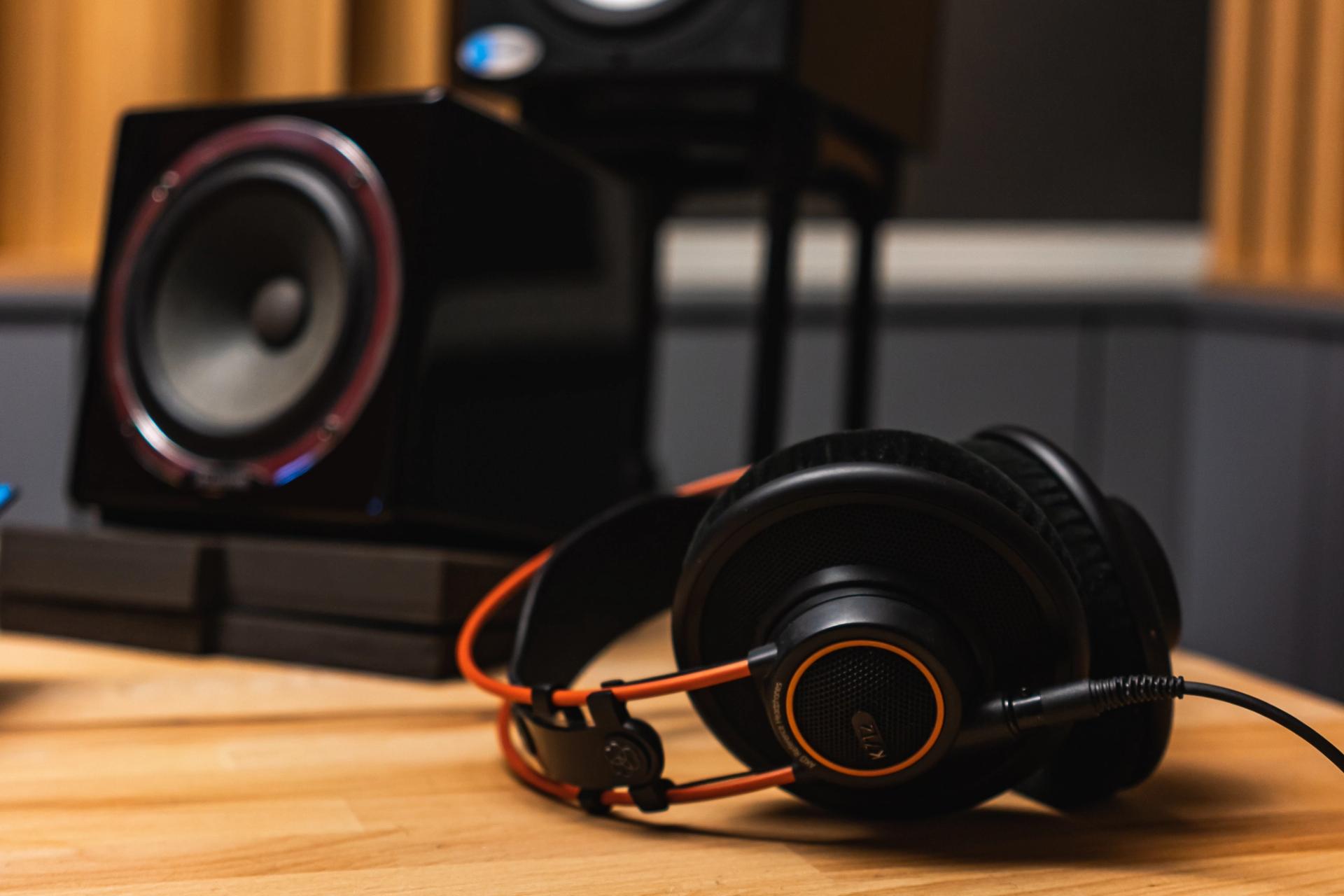 Offset picture of headset and speaker on hardwood surface inside recording studio