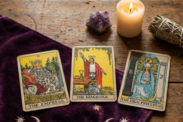 Drei Tarotkarten Die Herrscherin, Der Magier und Die Hohepriesterin auf violettem Tuch mit Mondsymbolen