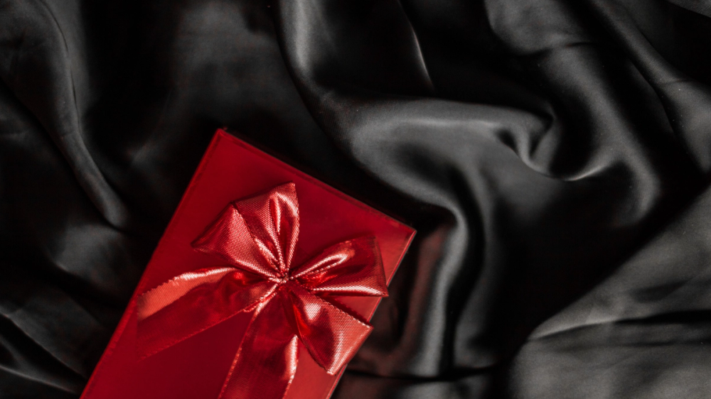 Perfektes Geschenk durch Venus-Stellung – rotes Geschenk auf schwarzem Seidentuch